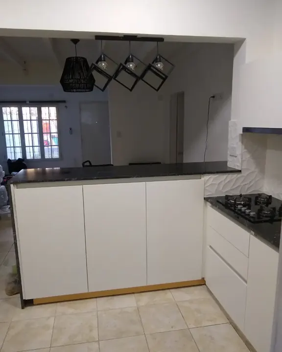 Cocina blanca a medida sin tiradores con perfil gola, desayunador con mesada negra y bajo mesada liso, fabricada en nuestro taller de General Roca