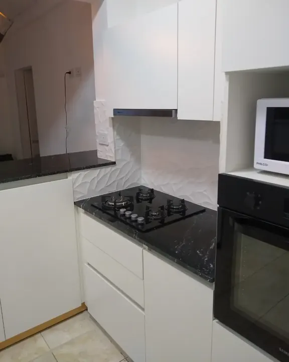 Bajo mesada blanco a medida con anafe, horno empotrado y microondas en nicho, cocina fabricada en nuestro taller de General Roca