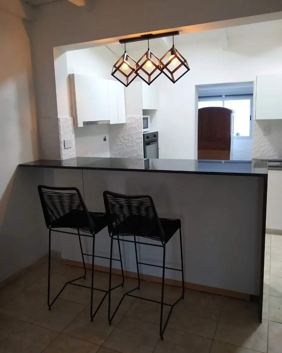 Cocina blanca a medida con desayunador, banquetas y mesada negra, fabricada en nuestro taller de General Roca