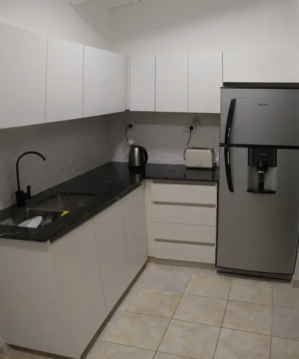 Bajo mesada y alacenas blancas sin tiradores junto a la heladera, cocina a medida con perfil gola fabricada en nuestro taller de General Roca