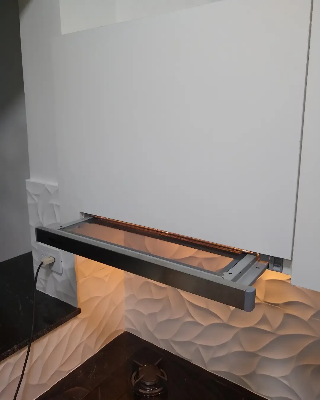 Campana extraíble con luz cálida bajo la alacena en una cocina blanca a medida sin tiradores, fabricada en nuestro taller de General Roca
