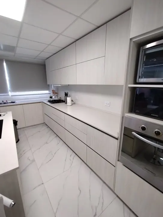 Cocina a medida en melamina Venezia con bajo mesada de cajones, alacenas hasta el techo y columna de hornos, fabricada en nuestro taller de General Roca