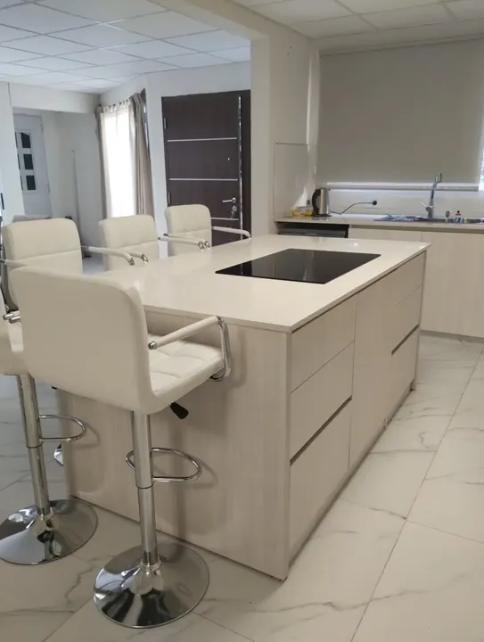 Cocina integral a medida en melamina Venezia, una madera clara, con isla y banquetas blancas, fabricada en nuestro taller de General Roca
