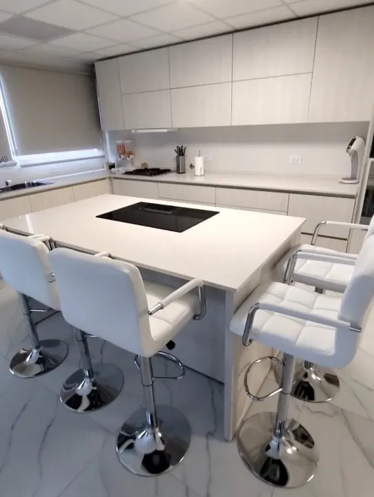 Cocina integral a medida en melamina Venezia con isla, anafe y banquetas blancas, fabricada en nuestro taller de General Roca
