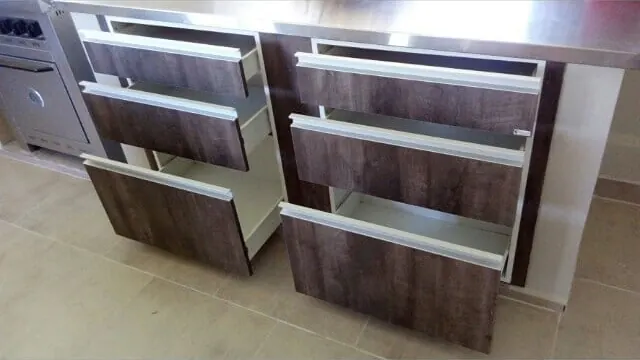 Cajones abiertos de una cocina a medida en melamina Terrarum con tiradores largos de aluminio, fabricada en nuestro taller de General Roca