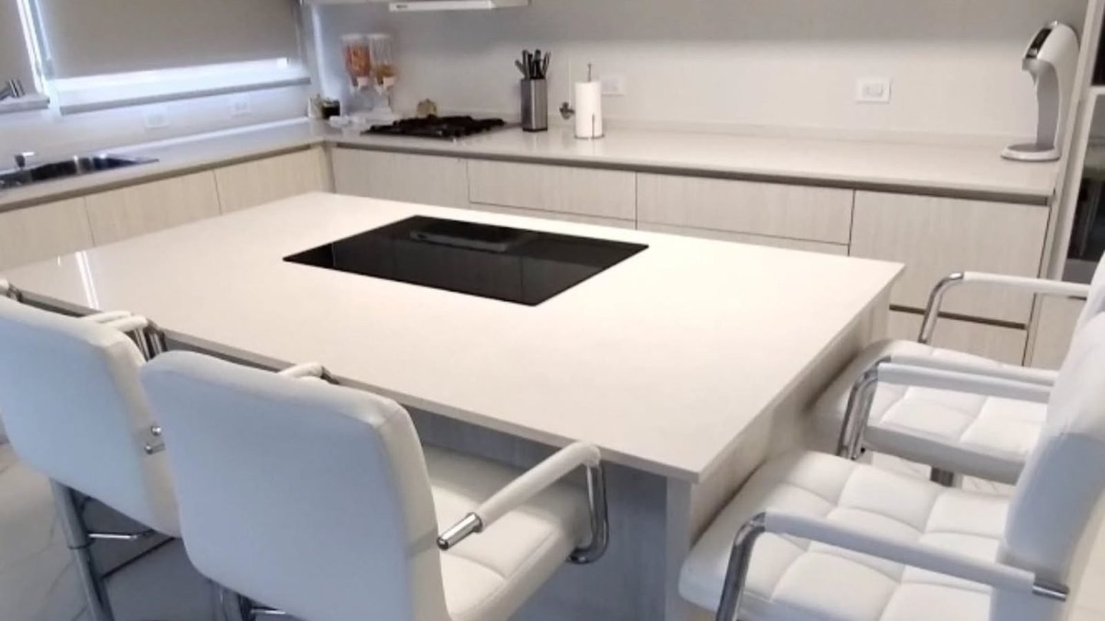 Cocina integral a medida en melamina Venezia con isla, anafe y banquetas blancas, fabricada en nuestro taller de General Roca