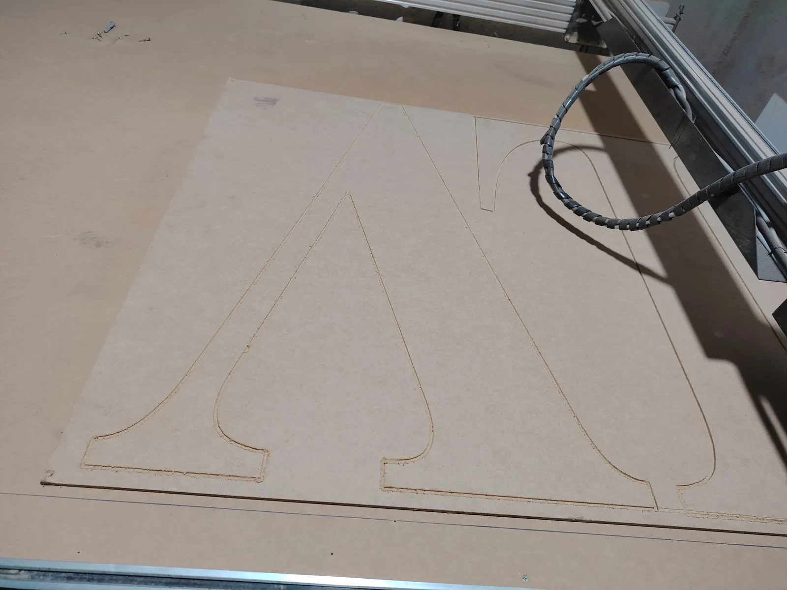 Router CNC cortando el contorno de letras grandes en una placa cruda en nuestro taller de General Roca